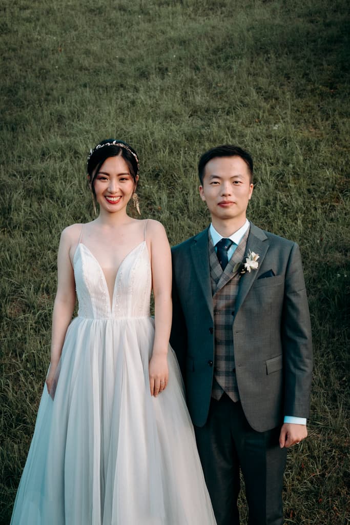 Portrait of the bride and groom in front of a green field