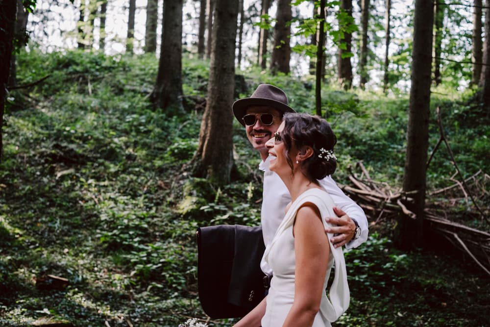 Wedding couple wandering through the forest in Munich having fun and laughing